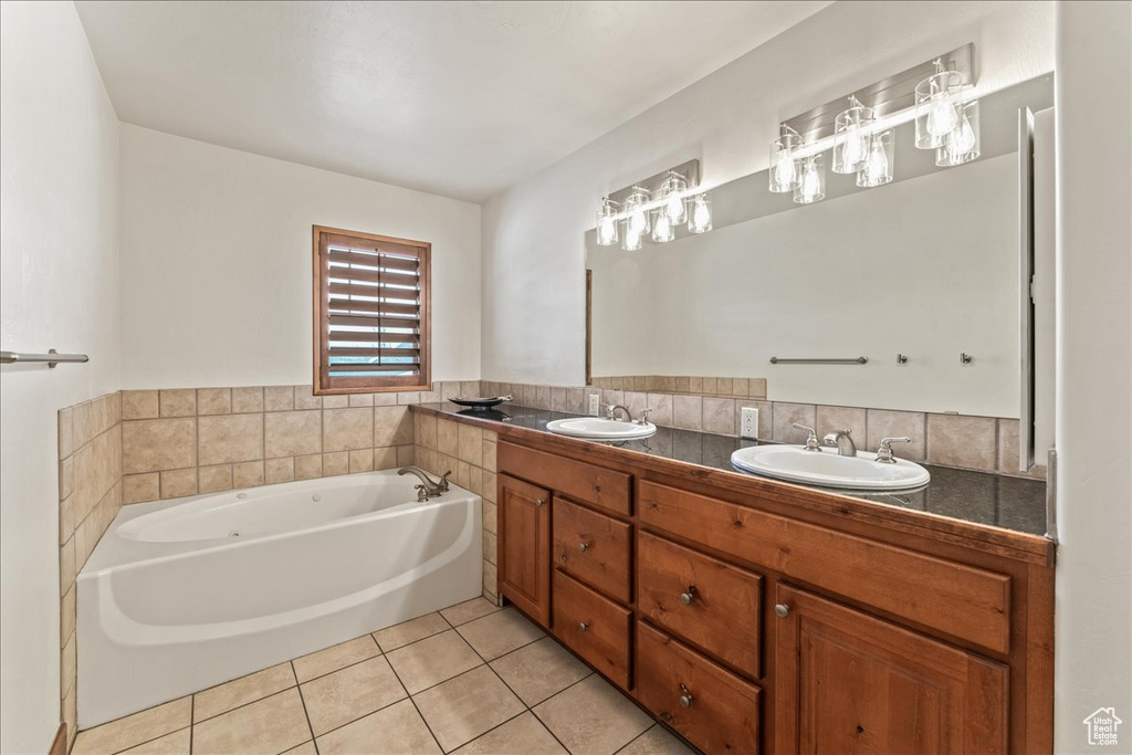 Bathroom with double sink, a washtub, vanity with extensive cabinet space, and tile flooring