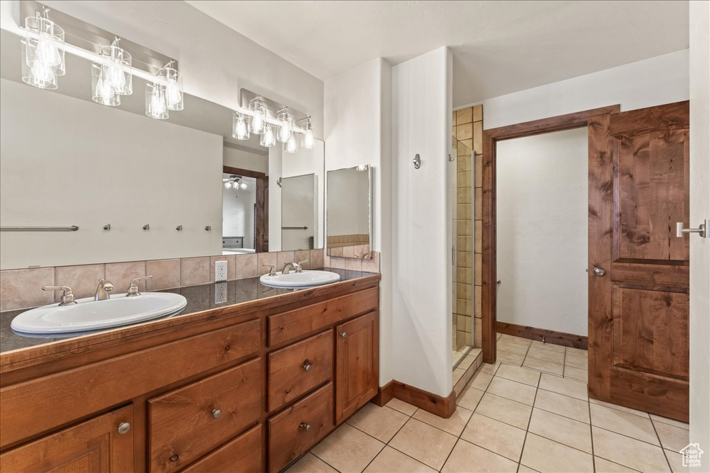 Bathroom with dual vanity, tile flooring, walk in shower, and backsplash