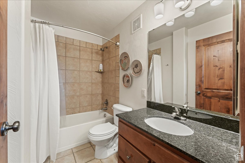 Full bathroom with oversized vanity, tile floors, toilet, and shower / tub combo with curtain