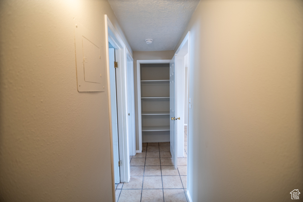 Corridor with a textured ceiling and light tile floors
