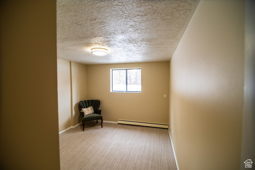 Unfurnished room featuring a baseboard radiator, light colored carpet, and a textured ceiling