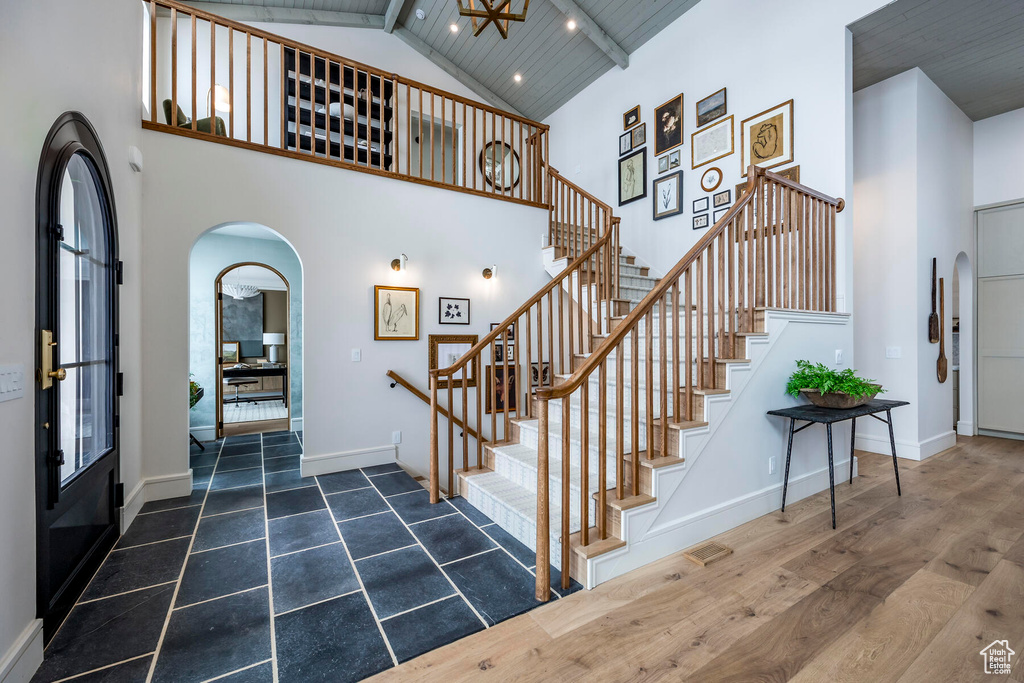 Staircase with beamed ceiling, wood ceiling, high vaulted ceiling, and dark hardwood / wood-style flooring