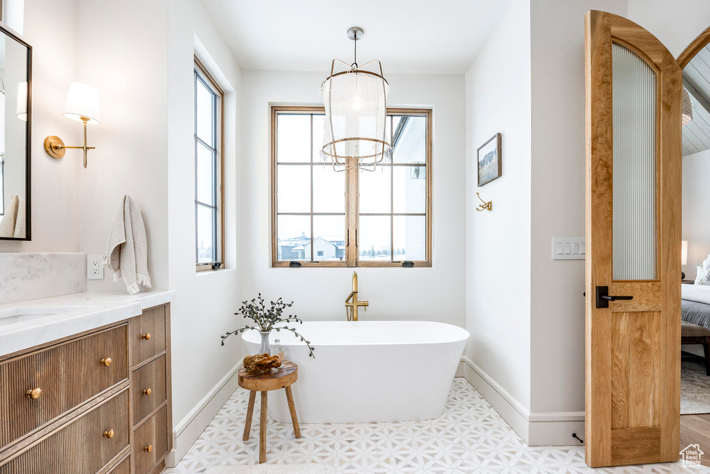 Bathroom with a bathtub, a notable chandelier, vanity, and tile flooring