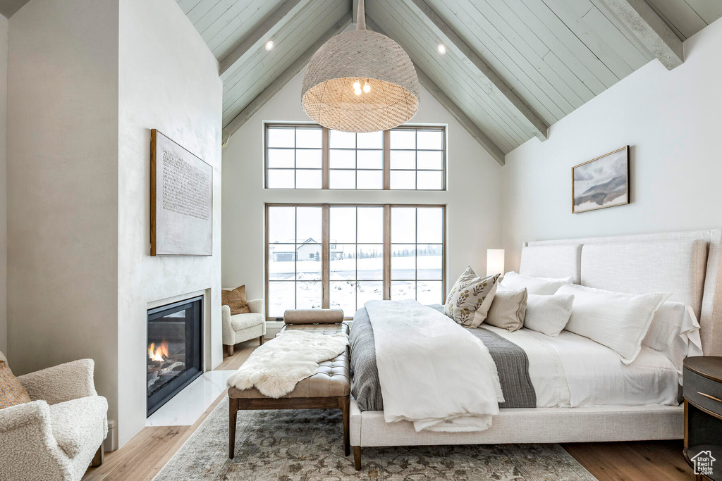 Bedroom with beamed ceiling, a fireplace, high vaulted ceiling, and hardwood / wood-style flooring