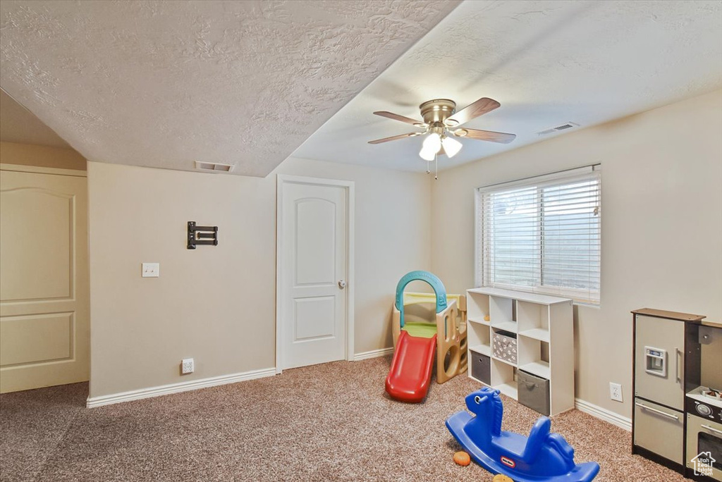 Rec room with dark carpet, a textured ceiling, and ceiling fan