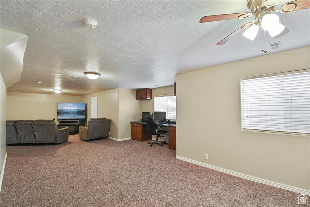 Carpeted living room featuring a textured ceiling and ceiling fan