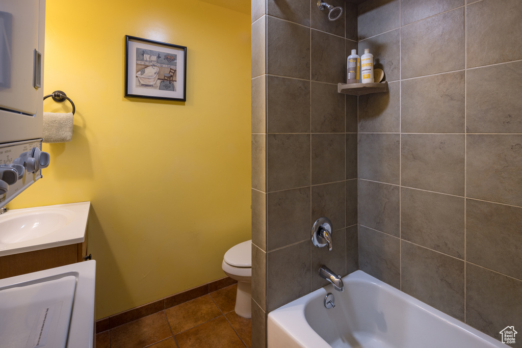 Full bathroom with tile floors, vanity, toilet, and tiled shower / bath