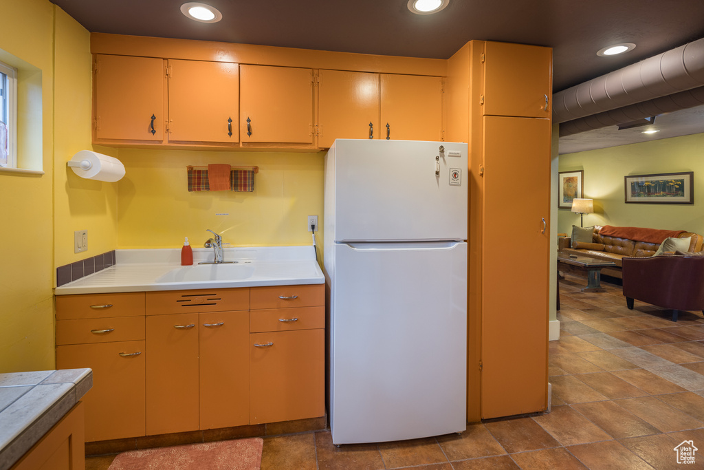 Kitchen with sink, white fridge, and light tile flooring