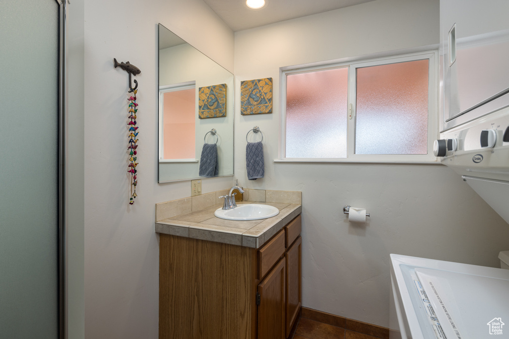 Bathroom featuring a bath, toilet, vanity with extensive cabinet space, and tile flooring