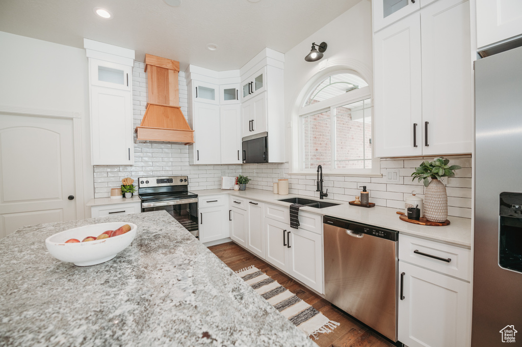 Kitchen featuring white cabinets, sink, stainless steel appliances, and custom range hood