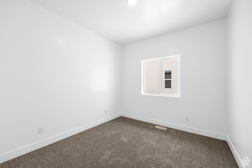 Unfurnished room featuring dark colored carpet