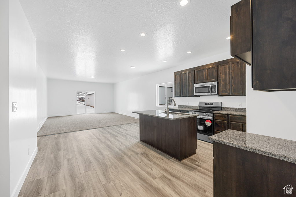 Kitchen with a center island with sink, sink, light hardwood / wood-style floors, and stainless steel appliances