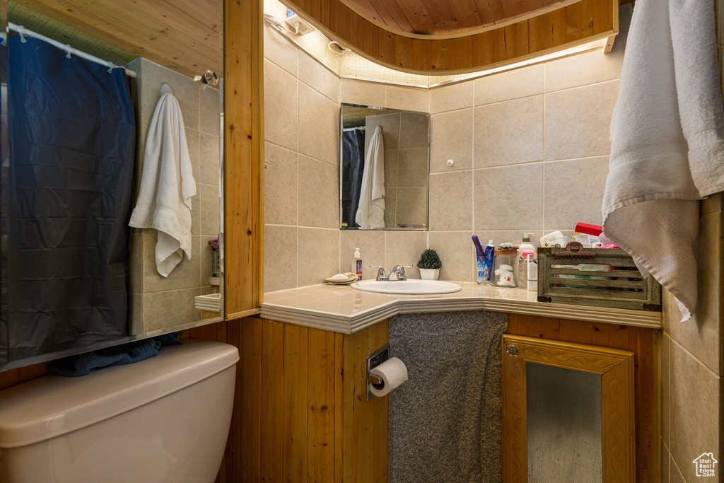 Bathroom featuring toilet, vanity, and wood ceiling