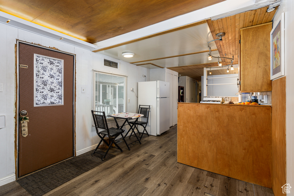 Kitchen featuring dark hardwood / wood-style floors, white fridge, kitchen peninsula, and wood ceiling