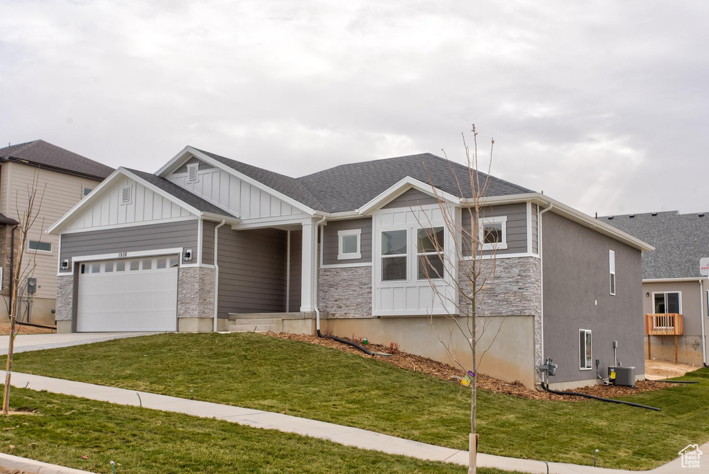 View of front of property featuring a garage, a front yard, and central AC