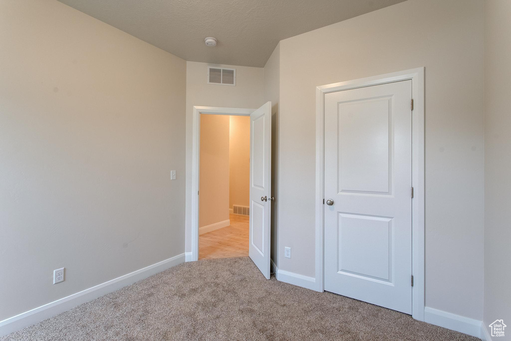 Unfurnished bedroom with light carpet