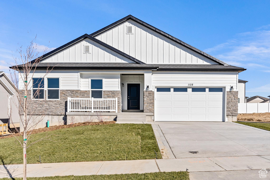 View of front of house featuring a garage, a front lawn, and a porch