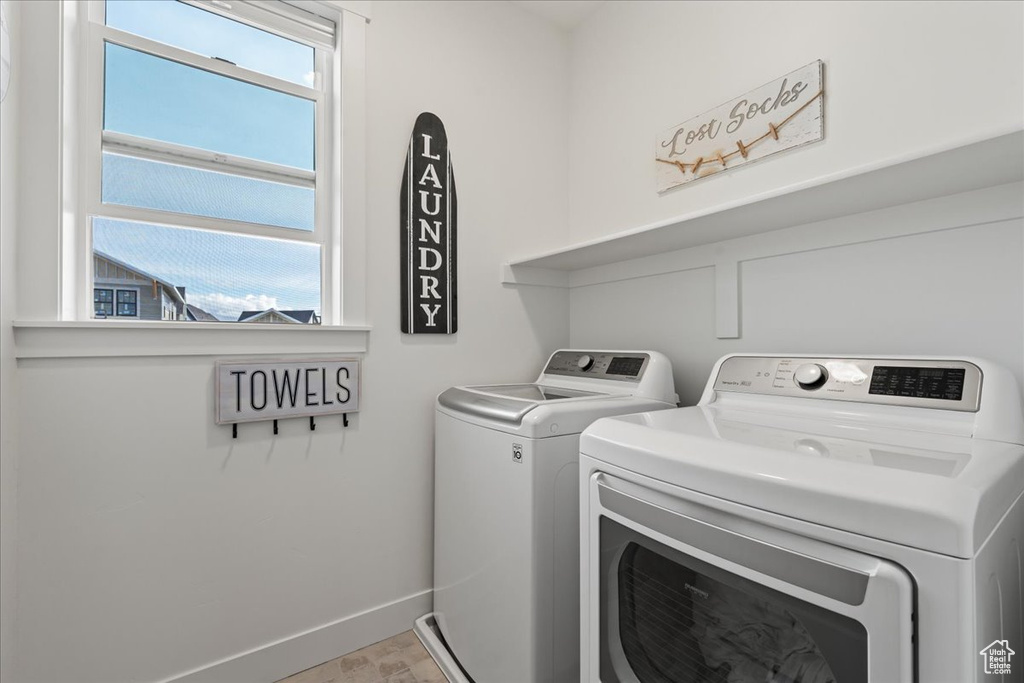 Laundry area with washer and clothes dryer and light tile floors