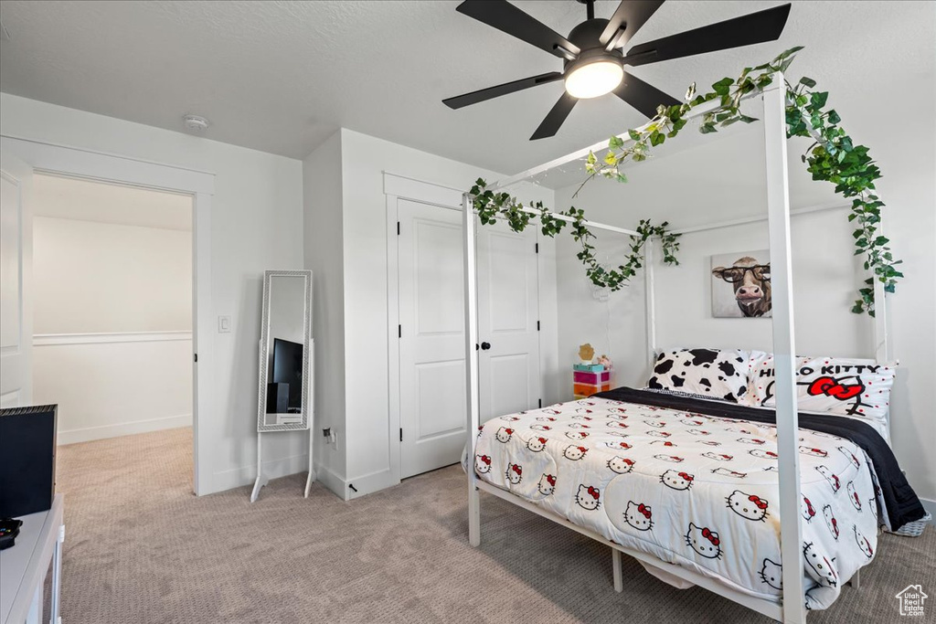 Bedroom featuring light colored carpet, a closet, and ceiling fan