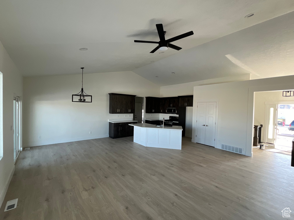 Unfurnished living room featuring sink, light wood-type flooring, ceiling fan, and lofted ceiling