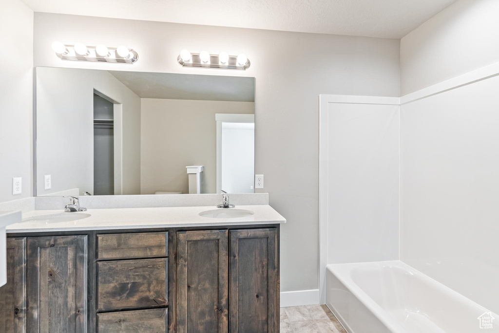 Full bathroom with shower / bathtub combination, toilet, dual vanity, and tile flooring