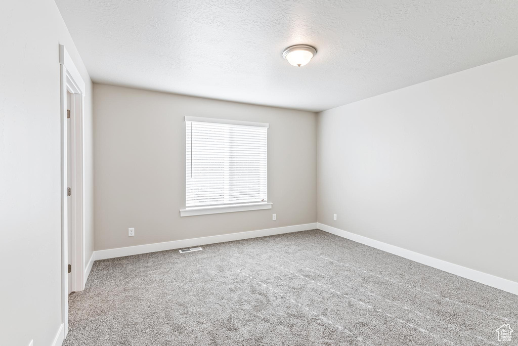 Carpeted empty room with a textured ceiling