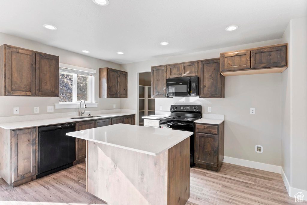 Kitchen featuring black appliances, sink, light hardwood / wood-style floors, and a center island