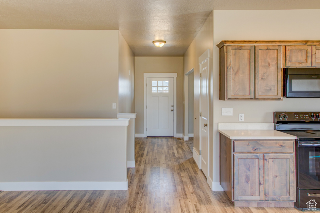 Kitchen with light hardwood / wood-style flooring and black appliances