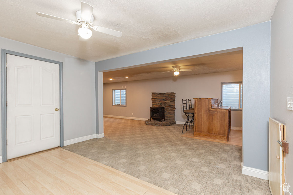 Unfurnished living room with a wood stove, light tile flooring, a fireplace, and ceiling fan