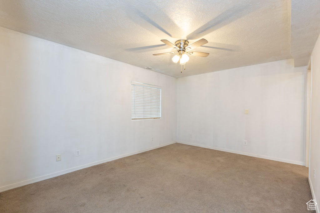 Unfurnished room with a textured ceiling, light colored carpet, and ceiling fan