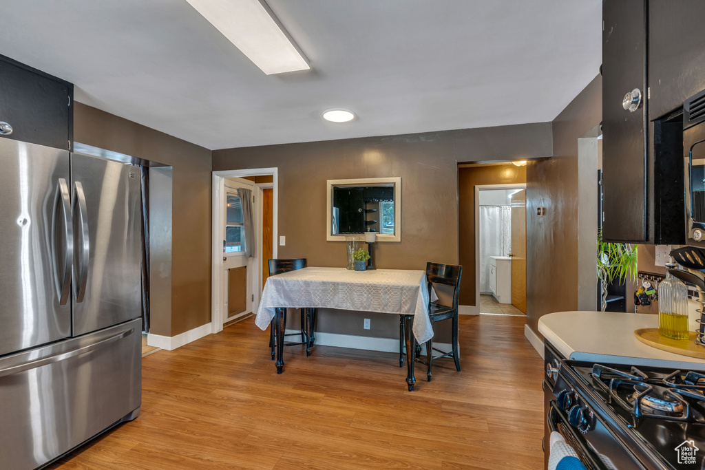 Kitchen featuring stainless steel refrigerator, light hardwood / wood-style flooring, and black / electric stove