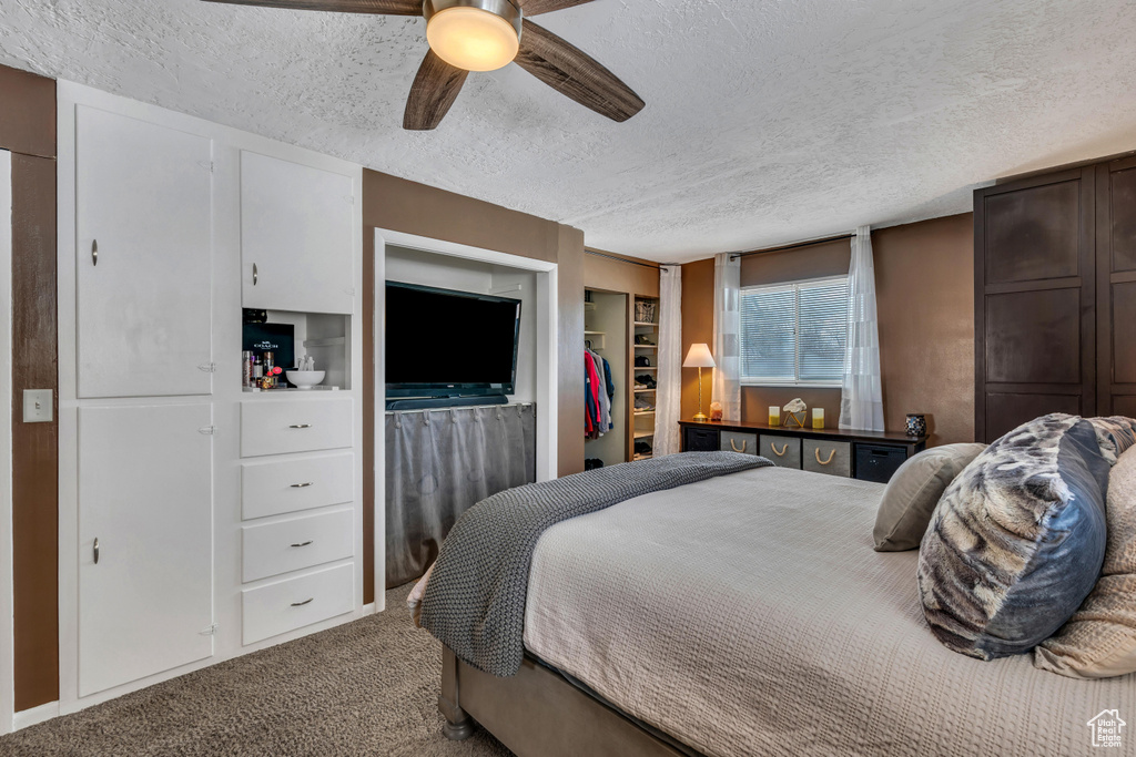 Carpeted bedroom featuring a closet, ceiling fan, and a textured ceiling