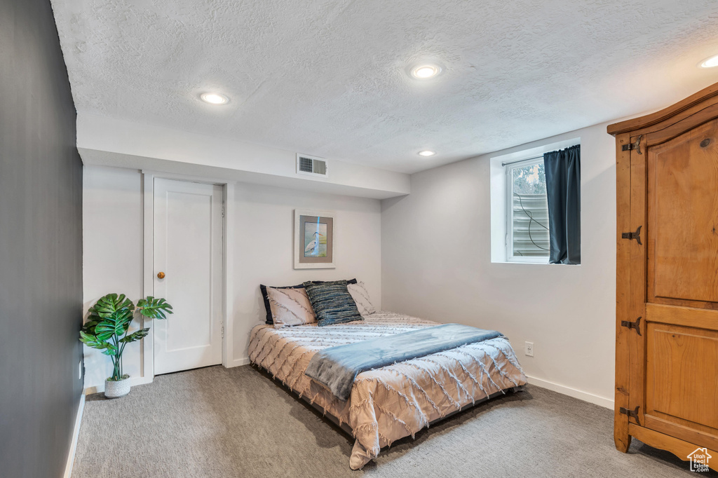 Bedroom featuring light carpet and a textured ceiling