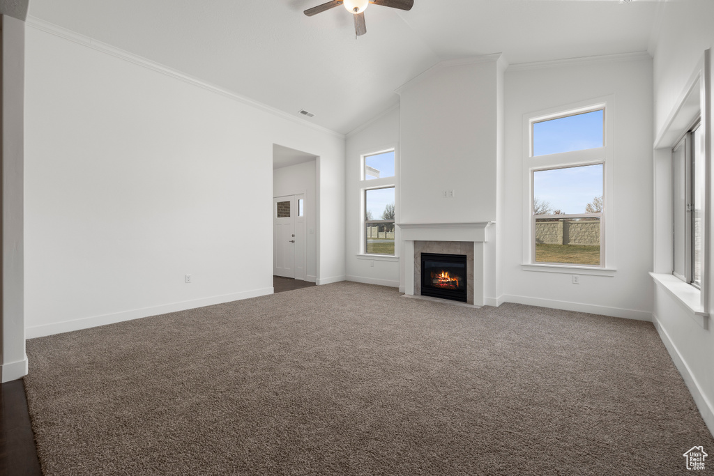 Unfurnished living room featuring ornamental molding, ceiling fan, a fireplace, and carpet flooring