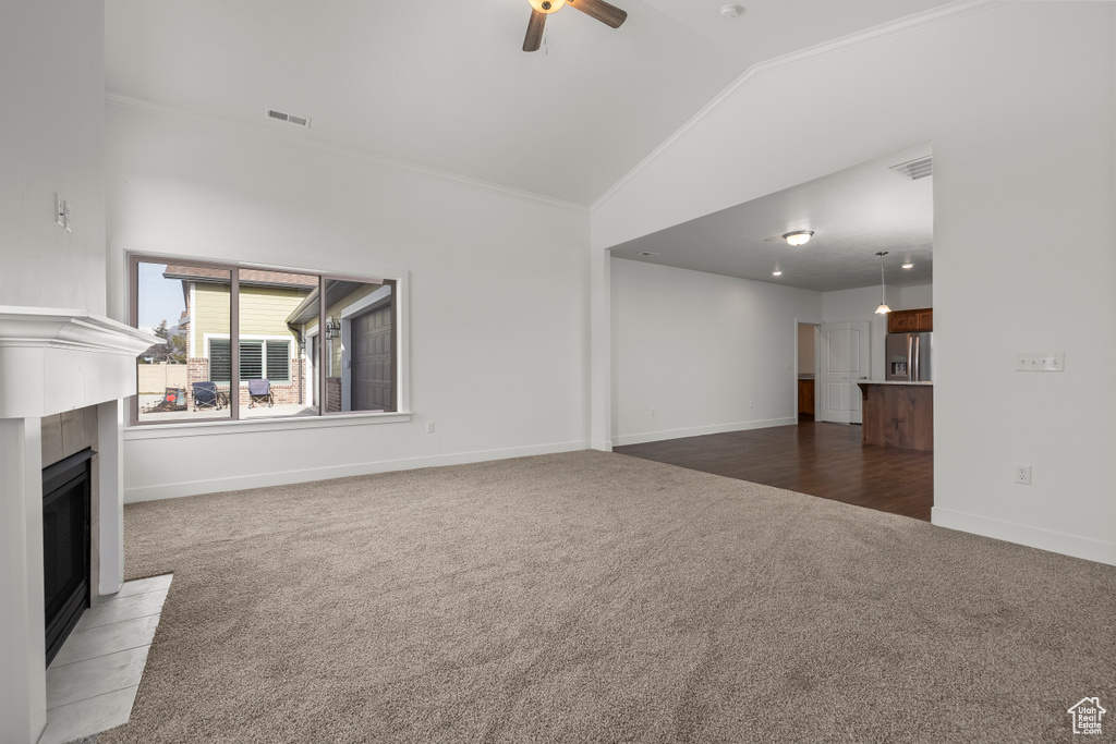 Unfurnished living room featuring ornamental molding, ceiling fan, a fireplace, and light carpet