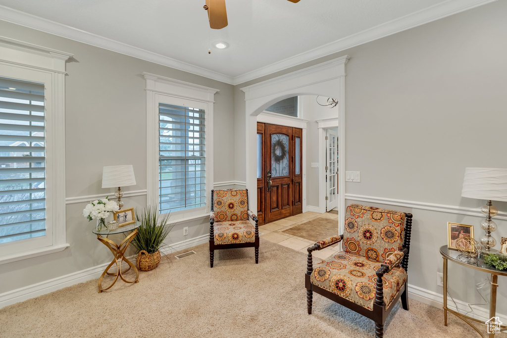 Living area featuring ornamental molding, light carpet, and ceiling fan