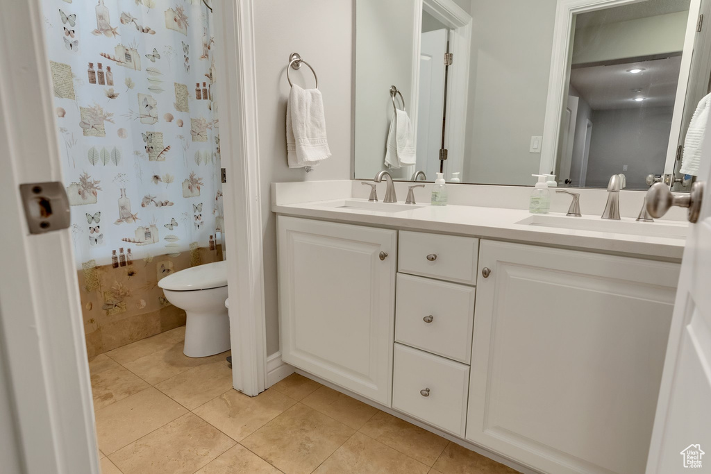 Bathroom with dual sinks, toilet, tile flooring, and oversized vanity