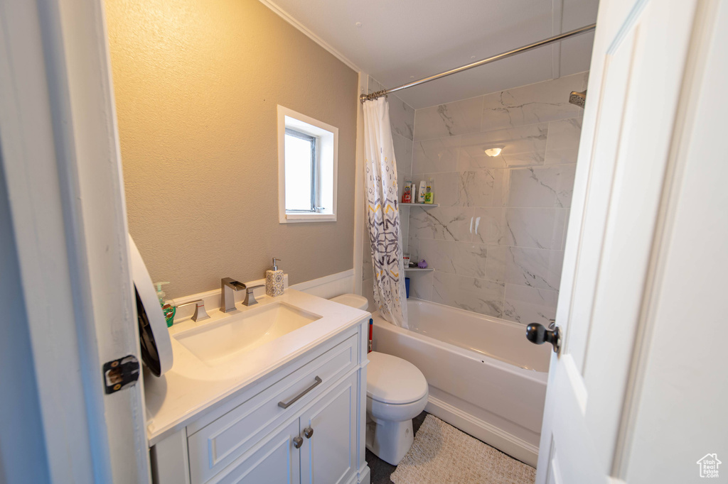 Full bathroom featuring shower / bath combination with curtain, toilet, and vanity with extensive cabinet space