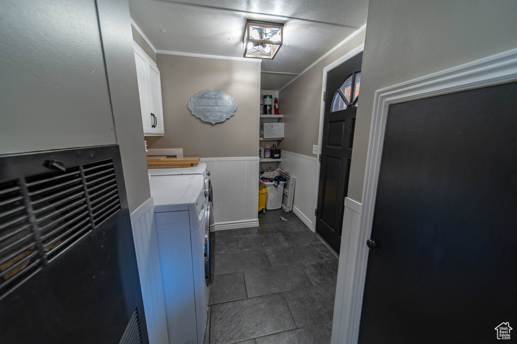 Laundry room with crown molding, cabinets, dark tile floors, and washing machine and dryer