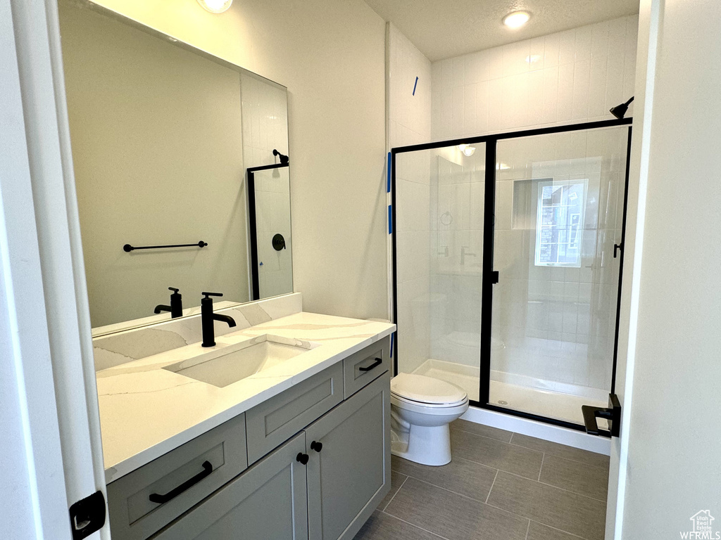 Bathroom featuring vanity, toilet, tile flooring, and an enclosed shower