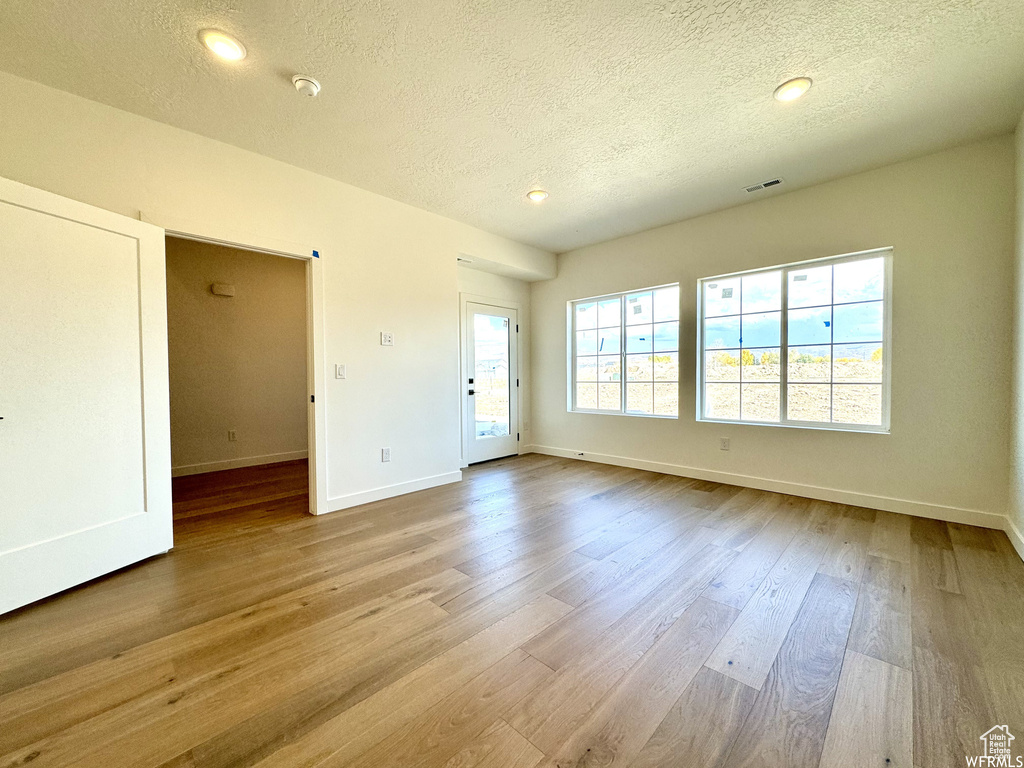 Empty room with hardwood / wood-style floors and a textured ceiling