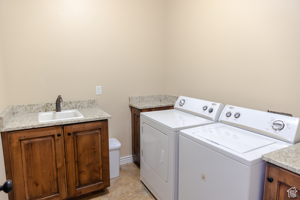 Laundry area featuring sink, light tile flooring, and washer and clothes dryer