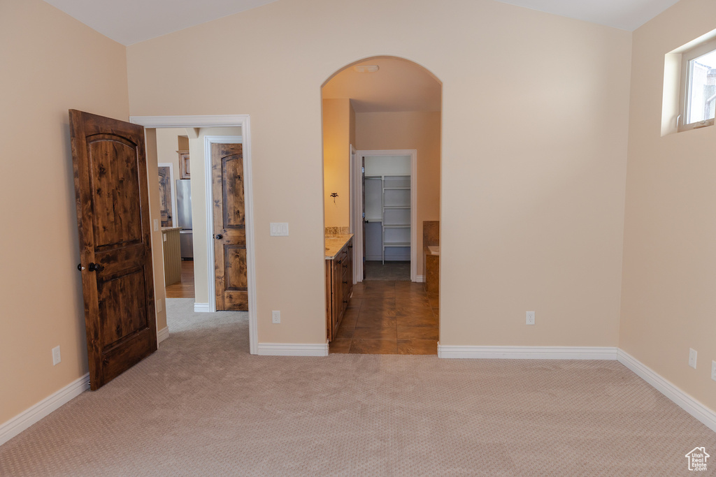 Empty room with vaulted ceiling and dark colored carpet