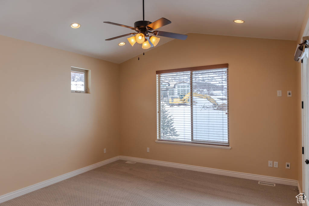 Carpeted spare room with a healthy amount of sunlight, vaulted ceiling, and ceiling fan