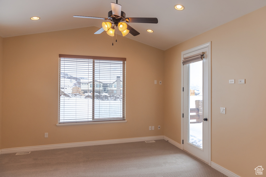 Carpeted spare room with lofted ceiling, a wealth of natural light, and ceiling fan