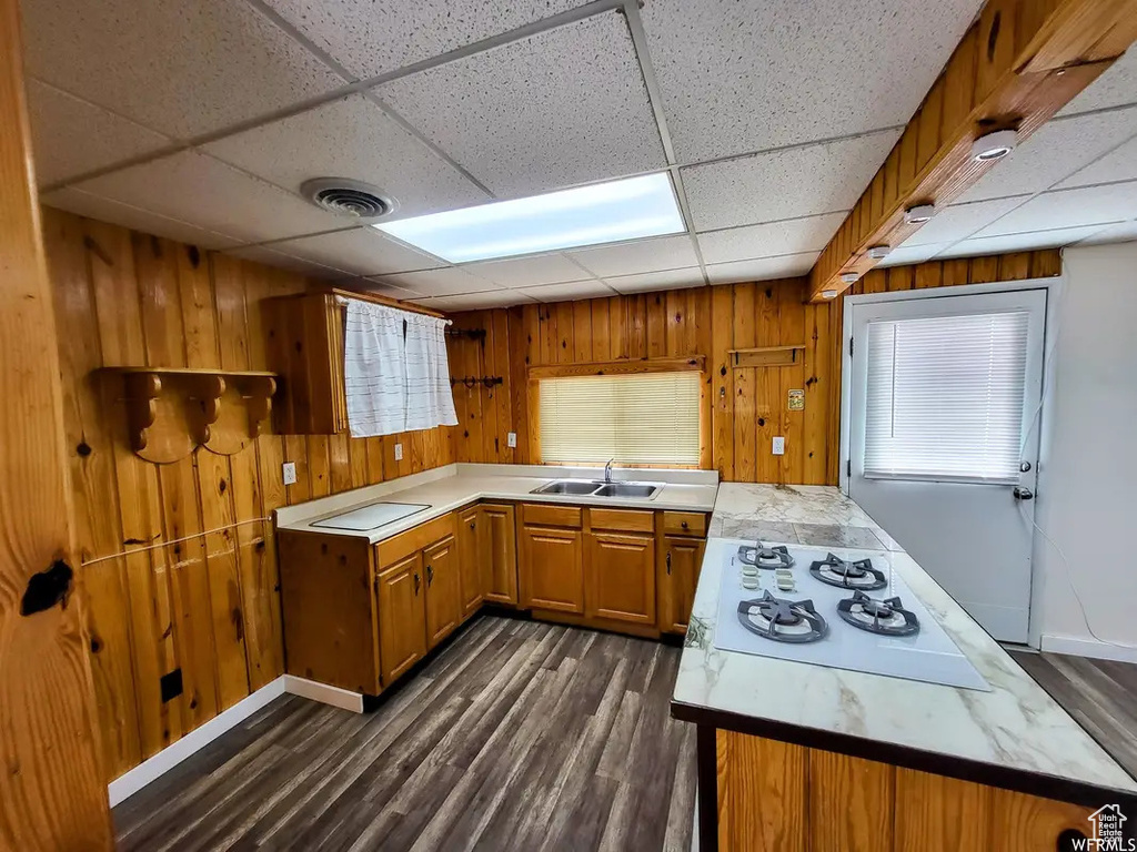Kitchen with dark hardwood / wood-style flooring, wooden walls, white gas stovetop, and a paneled ceiling