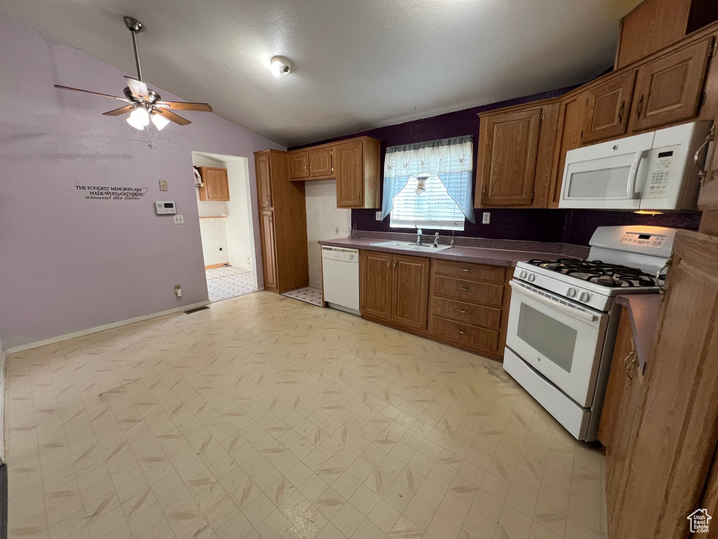 Kitchen featuring ceiling fan, light tile floors, lofted ceiling, white appliances, and sink