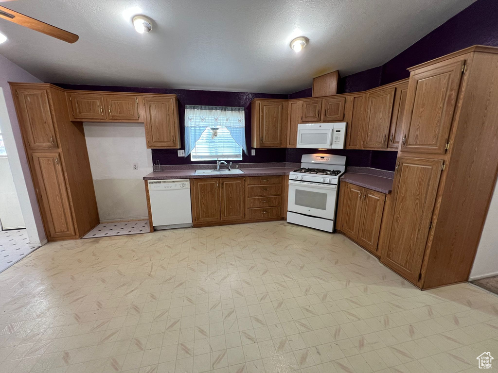Kitchen featuring sink, light tile flooring, white appliances, and ceiling fan