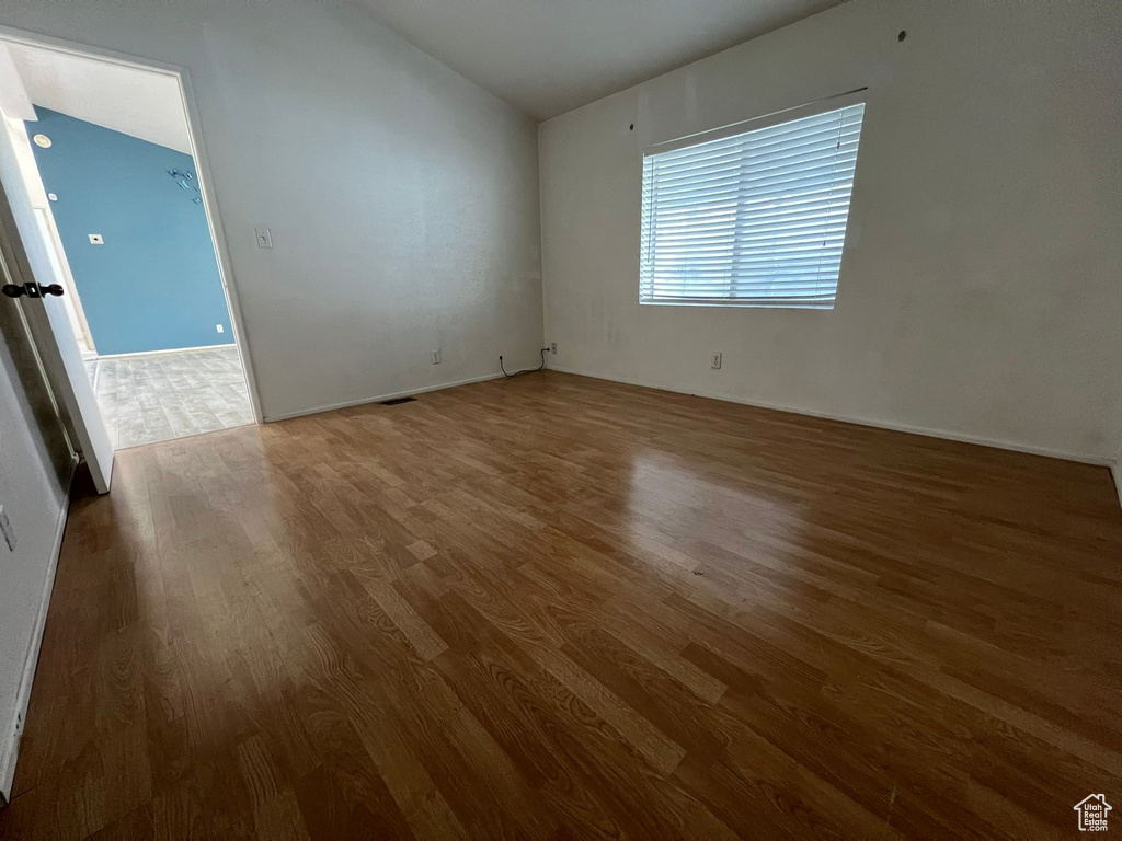 Empty room featuring vaulted ceiling and hardwood / wood-style flooring