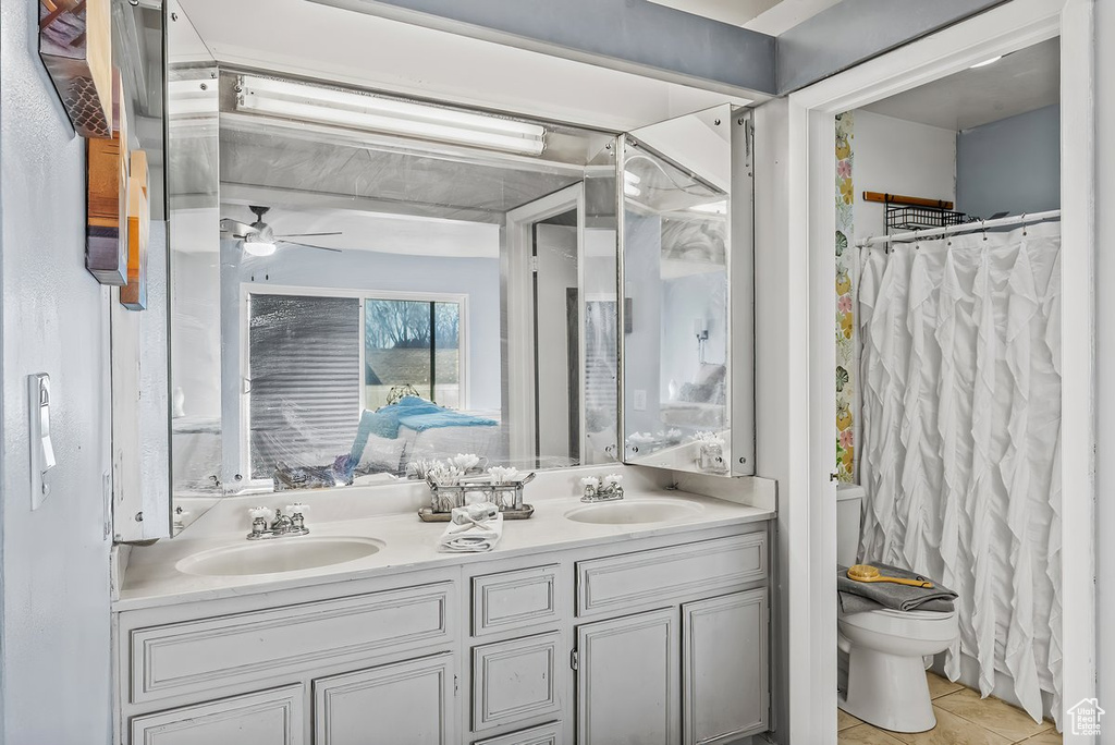 Bathroom featuring oversized vanity, toilet, ceiling fan, dual sinks, and tile floors